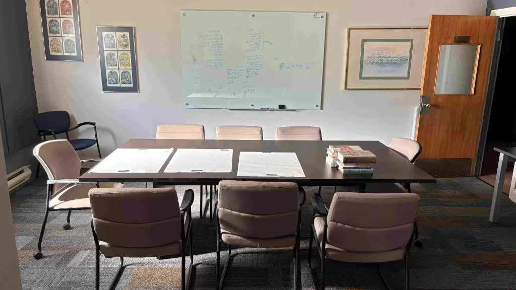 The Jack Miller Learning and Resource Centre, including a large table surrounded by chairs, a whiteboard, and framed artwork on the walls.