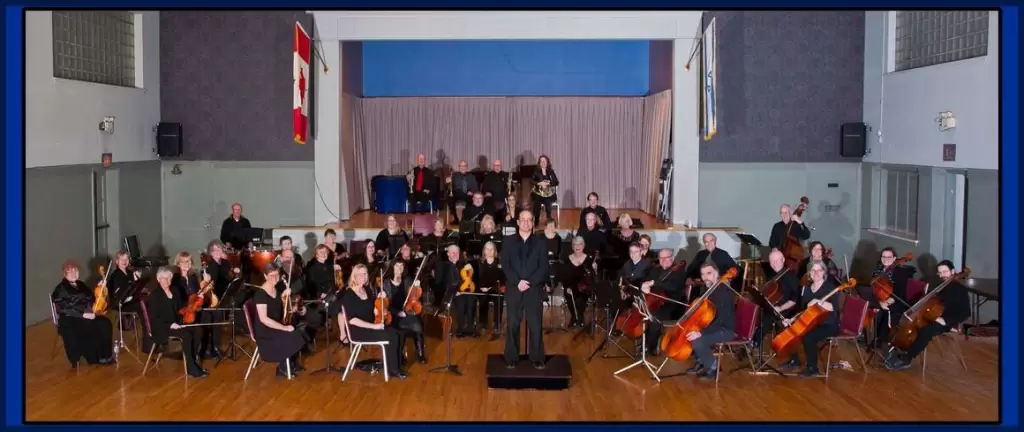 A concert in the auditorium featuring a large orchestra and a conductor in front.