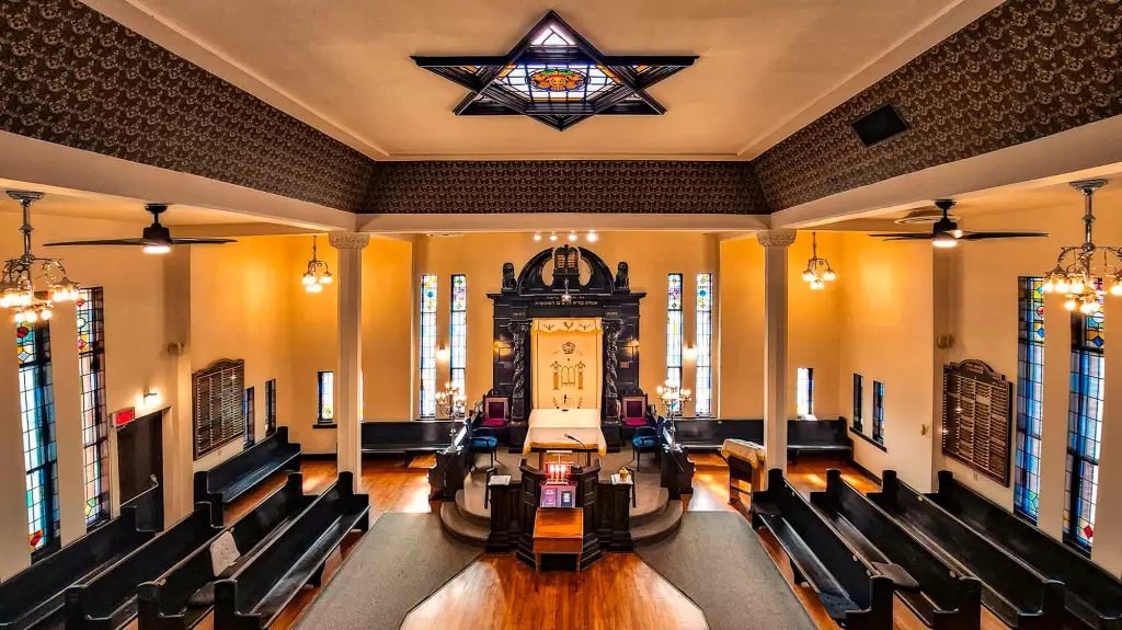 Interior of the Congregation B’nai Israel synagogue sanctuary, featuring an ornate ark, stained glass windows, and wooden pews.