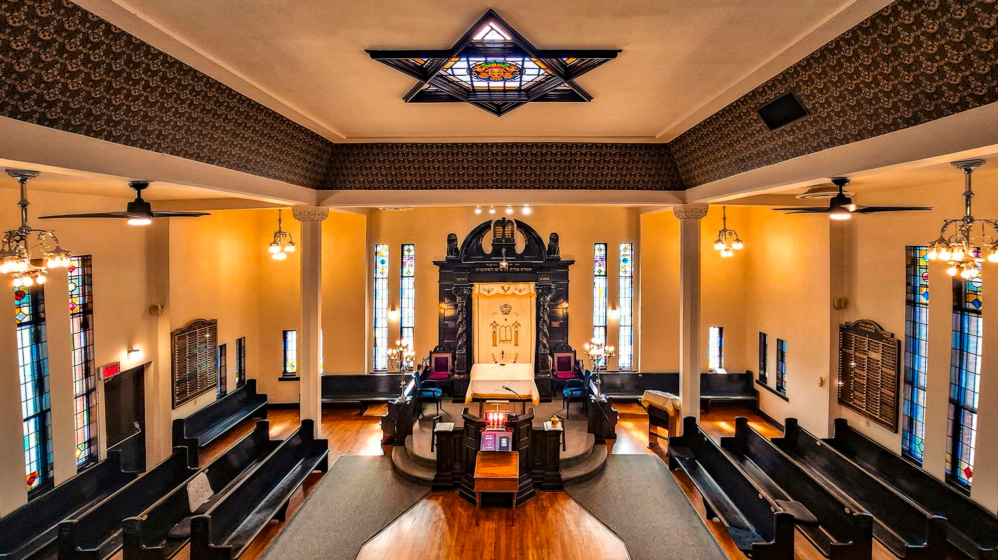 Interior of the Congregation B’nai Israel synagogue sanctuary, featuring an ornate ark, stained glass windows, and wooden pews.